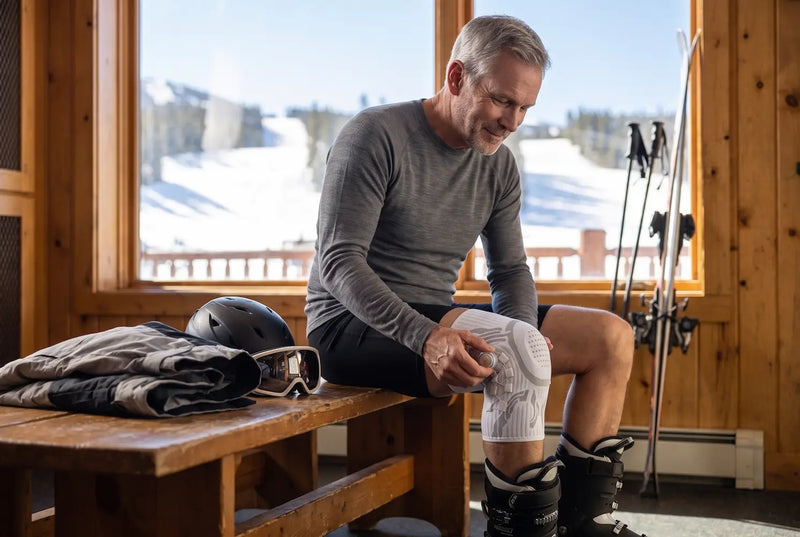 Skier tightening the Reoviva Dial Knee Support before the first run